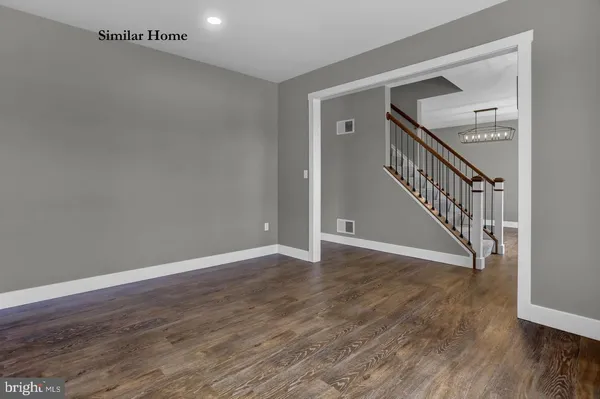 a view of an empty room with wooden floor and stairs