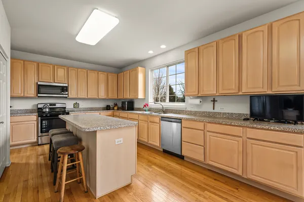 a kitchen with stainless steel appliances granite countertop a stove a sink a microwave and white cabinets