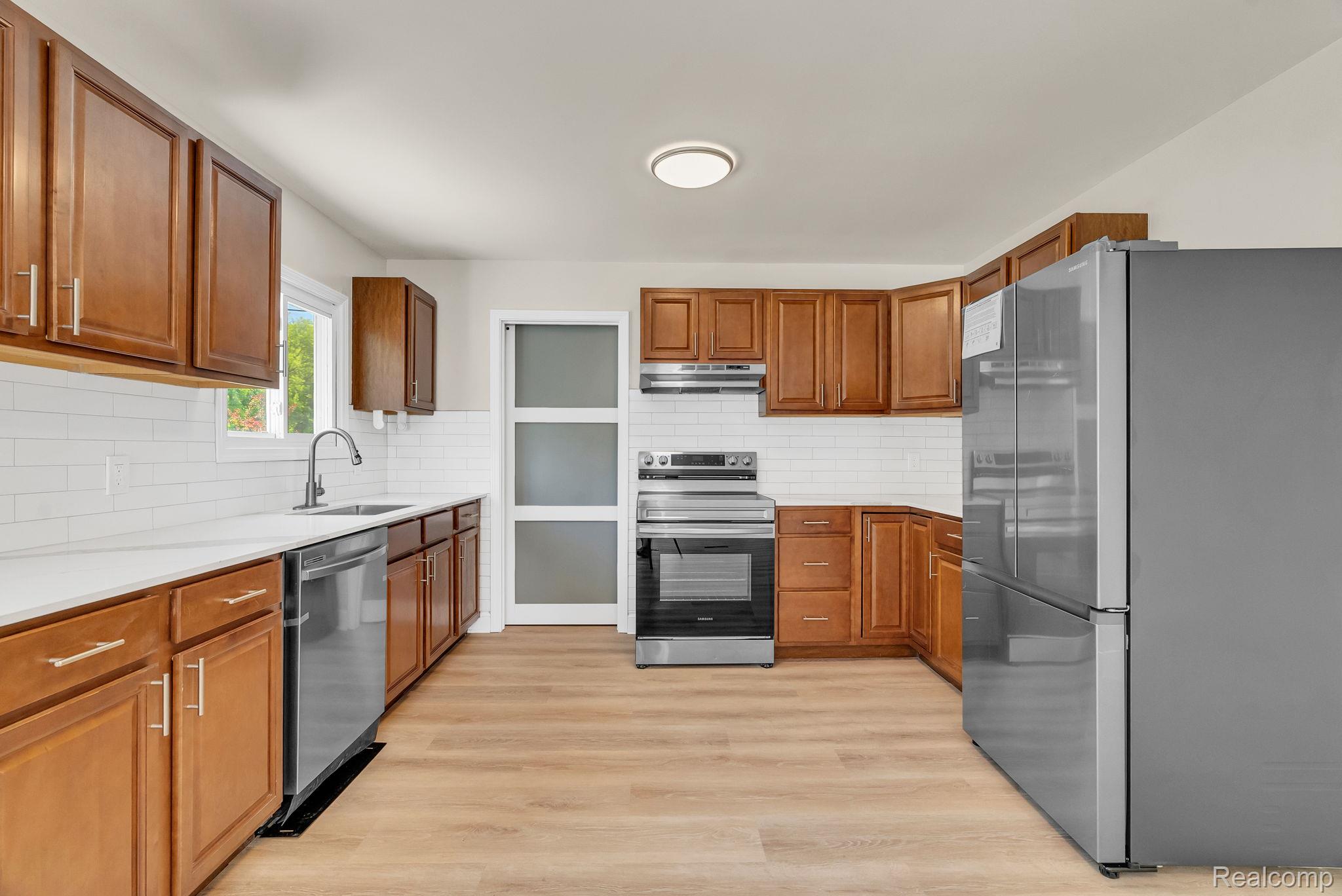 4046 State Road Fort Gratiot, MI 48059 - Photo 11 of 38 Kitchen featuring wood cabinetry, white subway tile backsplash, stainless steel appliances, white countertops, and wood-finish flooring