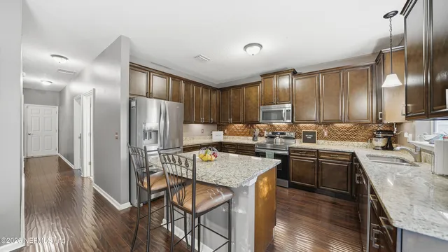 a kitchen with stainless steel appliances granite countertop a refrigerator a sink dishwasher a stove and white countertops with wooden floor