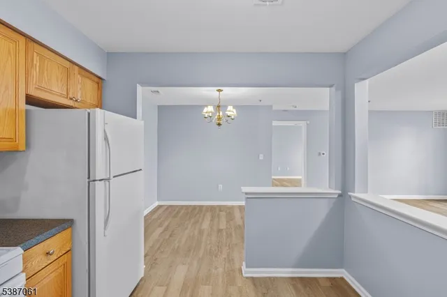 a view of kitchen with a refrigerator wooden cabinets and a window