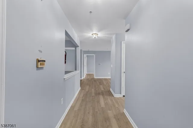 a view of a hallway with wooden floor and a bathroom