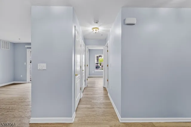a view of a hallway with wooden floor and a bathroom