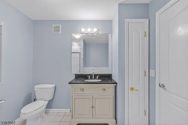 a bathroom with a granite countertop toilet a sink and a mirror