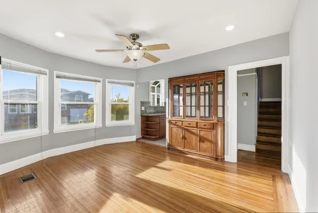 a view of an empty room with a window and wooden floor