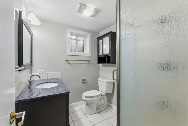 a bathroom with a granite countertop sink toilet and mirror