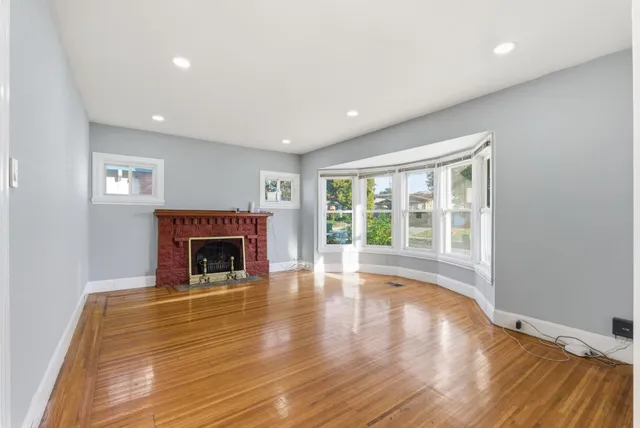 a view of empty room with wooden floor and fireplace