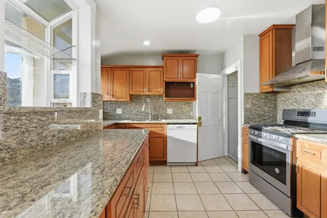 a kitchen with stainless steel appliances granite countertop a stove a sink and a microwave