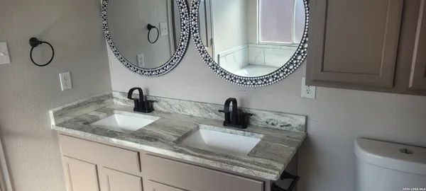 a bathroom with a granite countertop toilet a sink and mirror