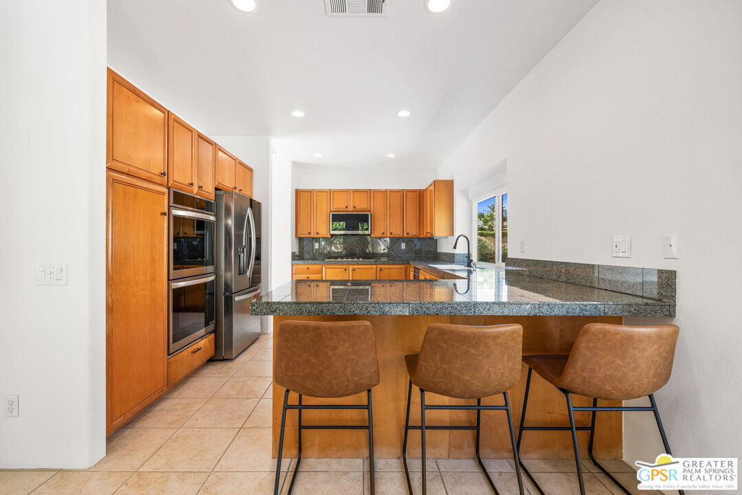 30 Vía Cielo Azul Palm Desert, CA 92260 - Photo 22 of 40 a kitchen with a table chairs refrigerator and cabinets