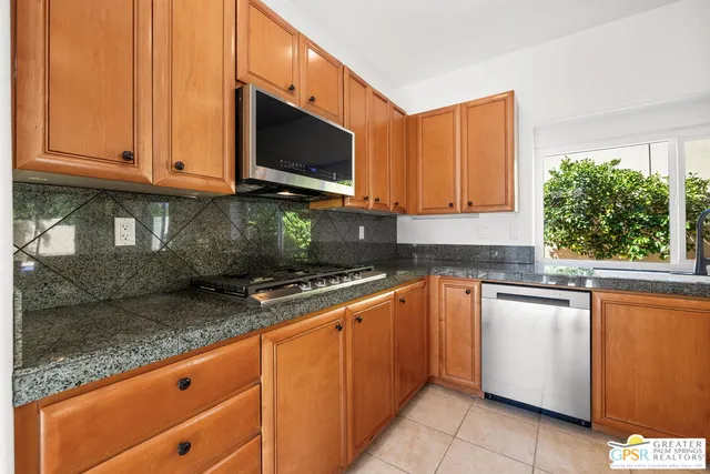 a kitchen with granite countertop stainless steel appliances a sink and a large window