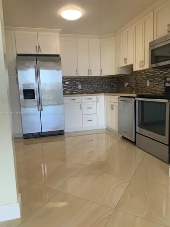 a kitchen with granite countertop a stove a sink and refrigerator