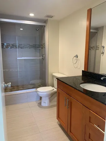 a bathroom with a granite countertop sink a toilet a mirror and shower