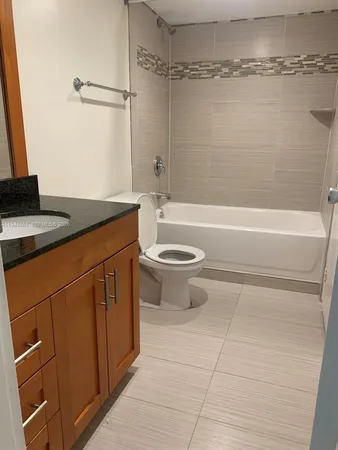 a bathroom with a granite countertop sink a toilet and bathtub