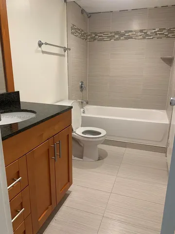 a bathroom with a granite countertop sink a toilet and bathtub