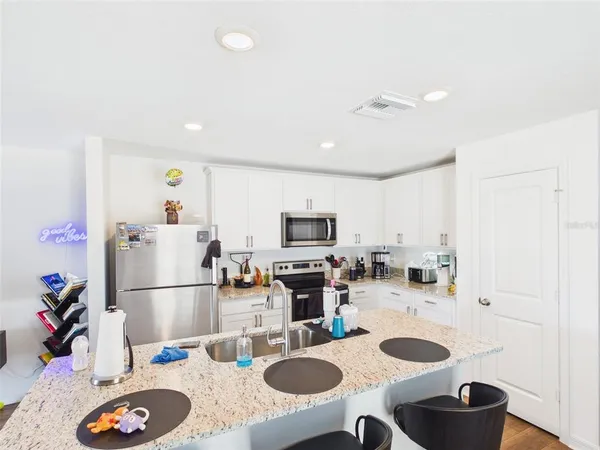 a kitchen with sink refrigerator dining table and chairs