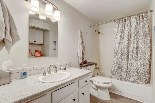 a bathroom with a granite countertop sink toilet a mirror a vanity and shower