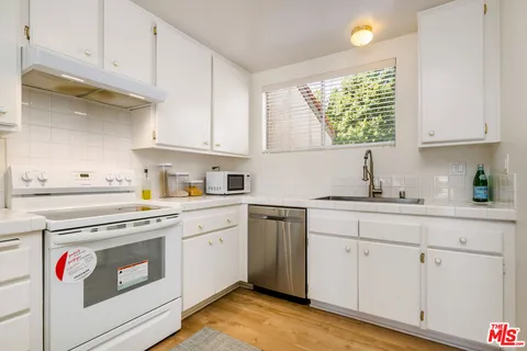 a kitchen with white cabinets and white appliances