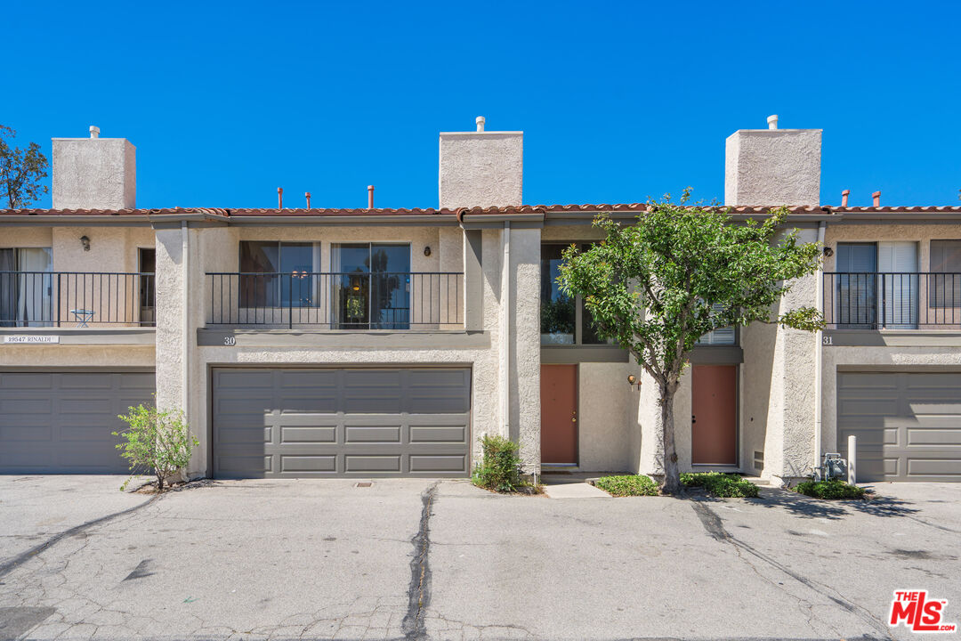 19547 Rinaldi Street, Unit 30 Porter Ranch, CA 91326 - Photo 2 of 33 a front view of a house with a yard and garage