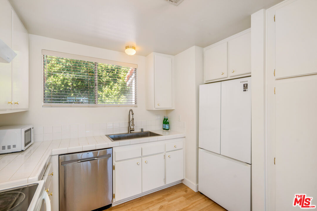 19547 Rinaldi Street, Unit 30 Porter Ranch, CA 91326 - Photo 21 of 33 a kitchen with stainless steel appliances white cabinets and a window