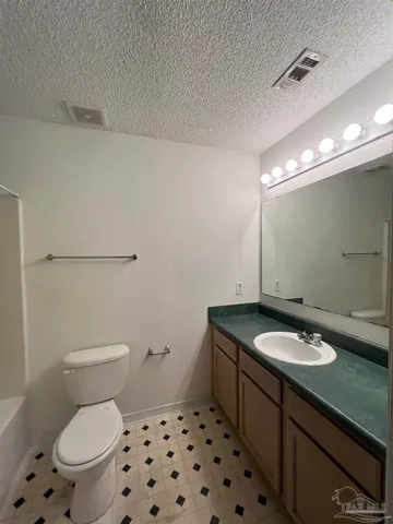 a bathroom with a granite countertop toilet a sink and a mirror