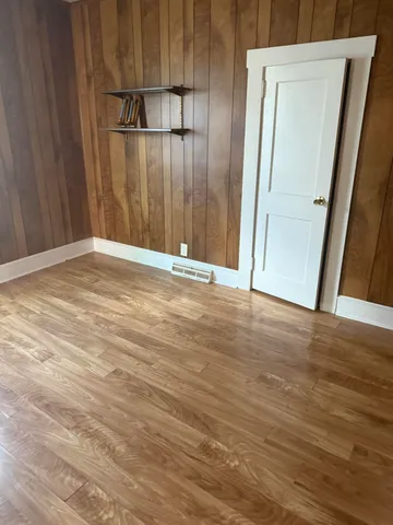 a view of an empty room with wooden floor and a mirror