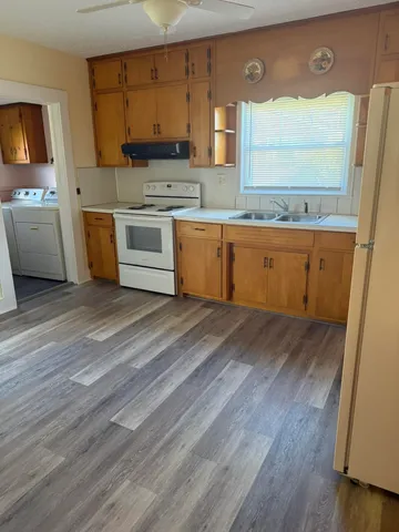 a view of a kitchen with a sink dishwasher stove and wooden floor