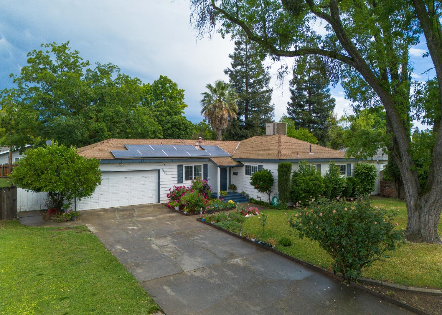 Single story home featuring solar panels, a garage, driveway, Situated on a spacious 0.25-acre lot