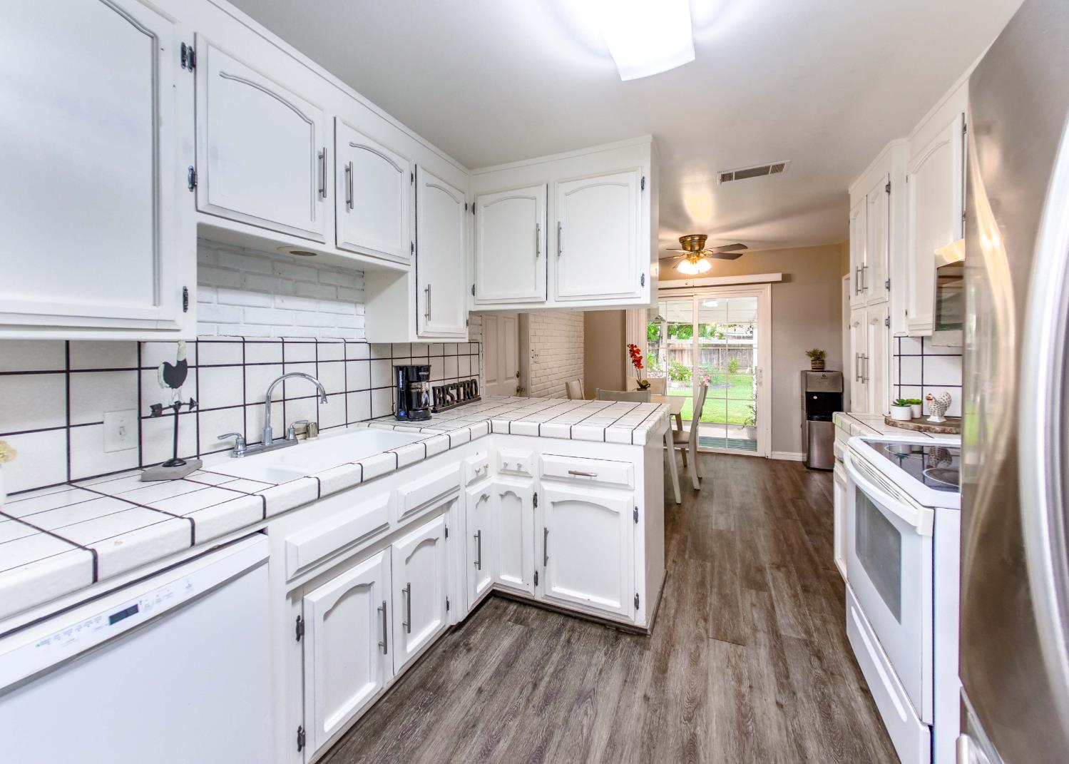 2952 Tahoe Drive Merced, CA 95340 - Photo 16 of 70 kitchen with tile countertops, stainless steel appliances, white cabinets, backsplash, and ceiling fan