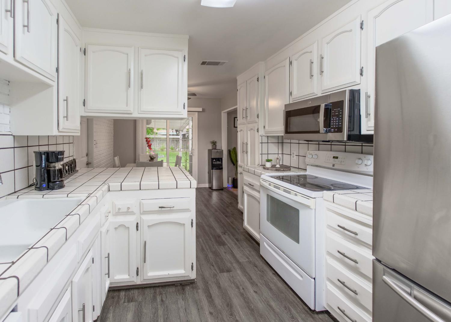 2952 Tahoe Drive Merced, CA 95340 - Photo 4 of 70 kitchen with stainless steel appliances, white cabinetry, tile countertops, dark wood-style floors, and a peninsula