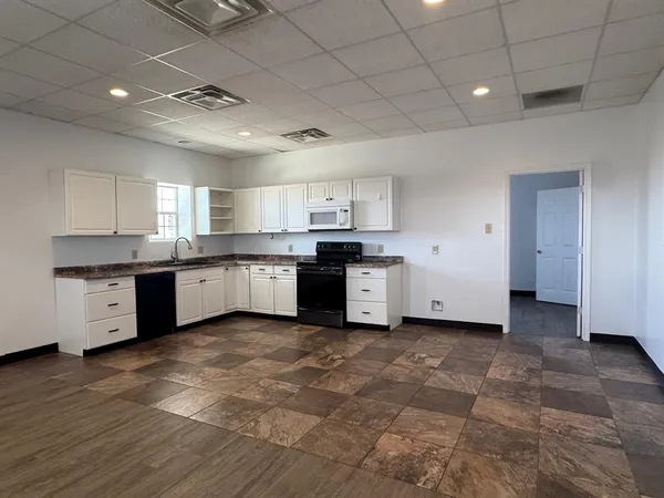 a large kitchen with cabinets a sink a window and stainless steel appliances