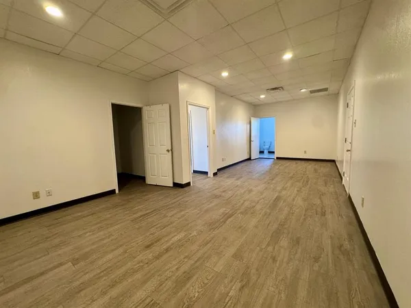 an empty room with wooden floor and natural light
