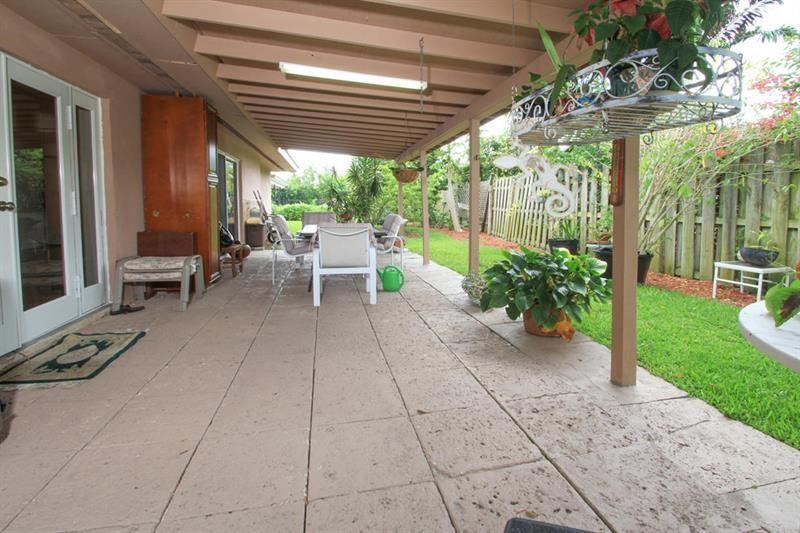 98 Seminole Lane Boca Raton, FL 33487 - Photo 15 of 42 a view of a patio with table and chairs potted plants and floor to ceiling window