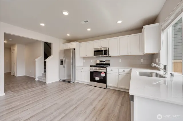 a kitchen with white cabinets and stainless steel appliances