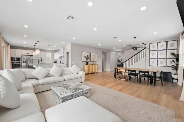 a living room with furniture kitchen view and a large window