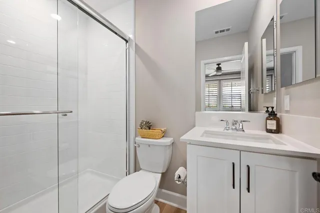 a bathroom with a sink a toilet a mirror and shower