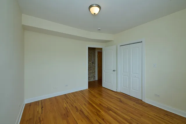 a view of an empty room with wooden floor and windows