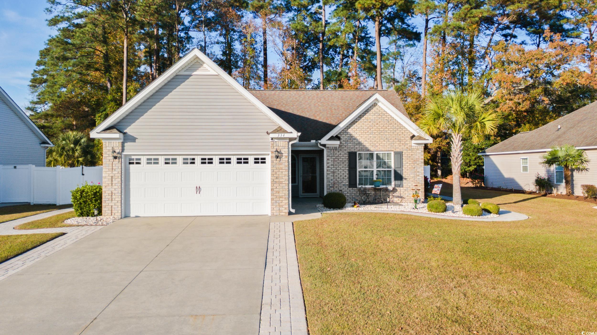 Traditional-style home featuring concrete driveway, brick siding, an attached garage, and a shingled roof