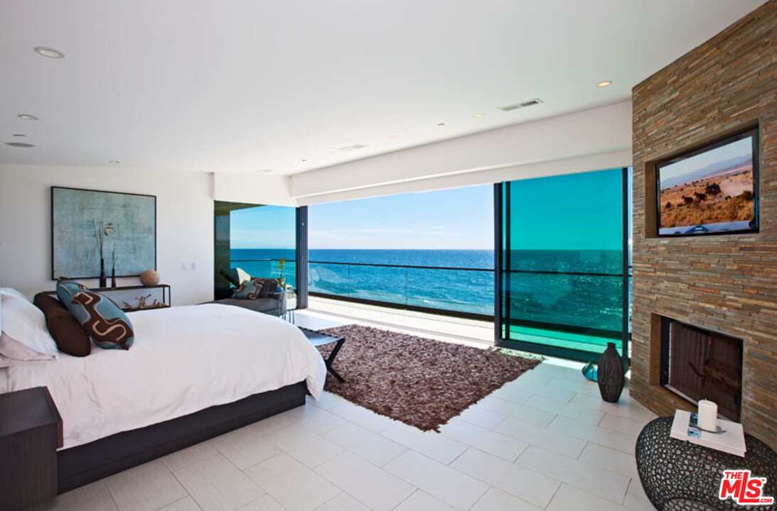 25250 Malibu Road Malibu, CA 90265 - Photo 17 of 31 a bedroom with a bed a fireplace and a large window