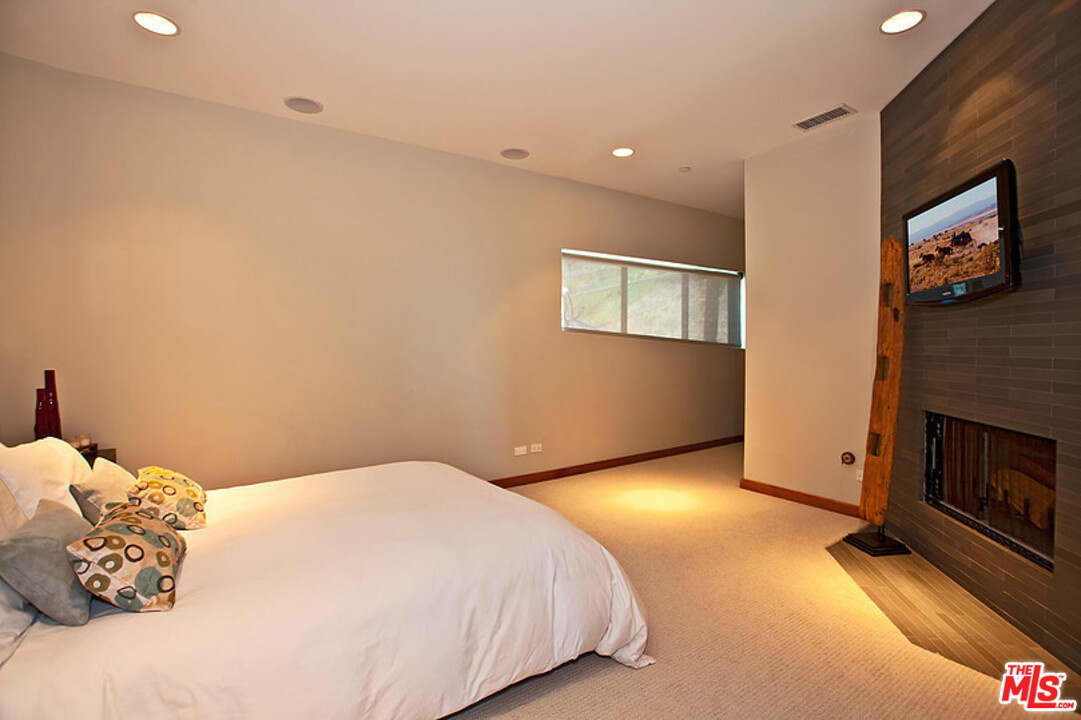 25250 Malibu Road Malibu, CA 90265 - Photo 27 of 31 a bedroom with a bed and a fireplace