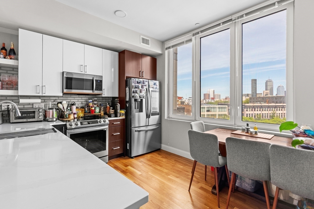 10 Taber Street, Unit 508 Boston, MA 02119 - Photo 6 of 11 a kitchen with stainless steel appliances granite countertop a stove a refrigerator a kitchen island a table and chairs