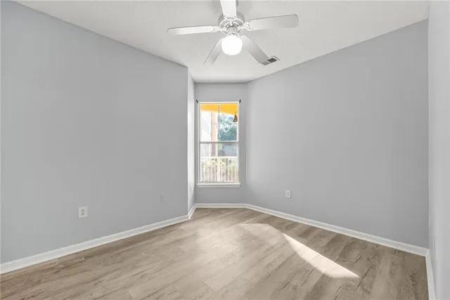 an empty room with a window and a fan