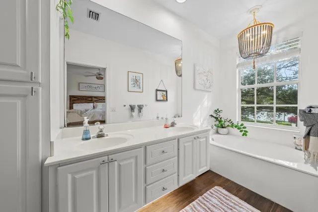 a spacious bathroom with a sink a large mirror and a bathtub next to a window