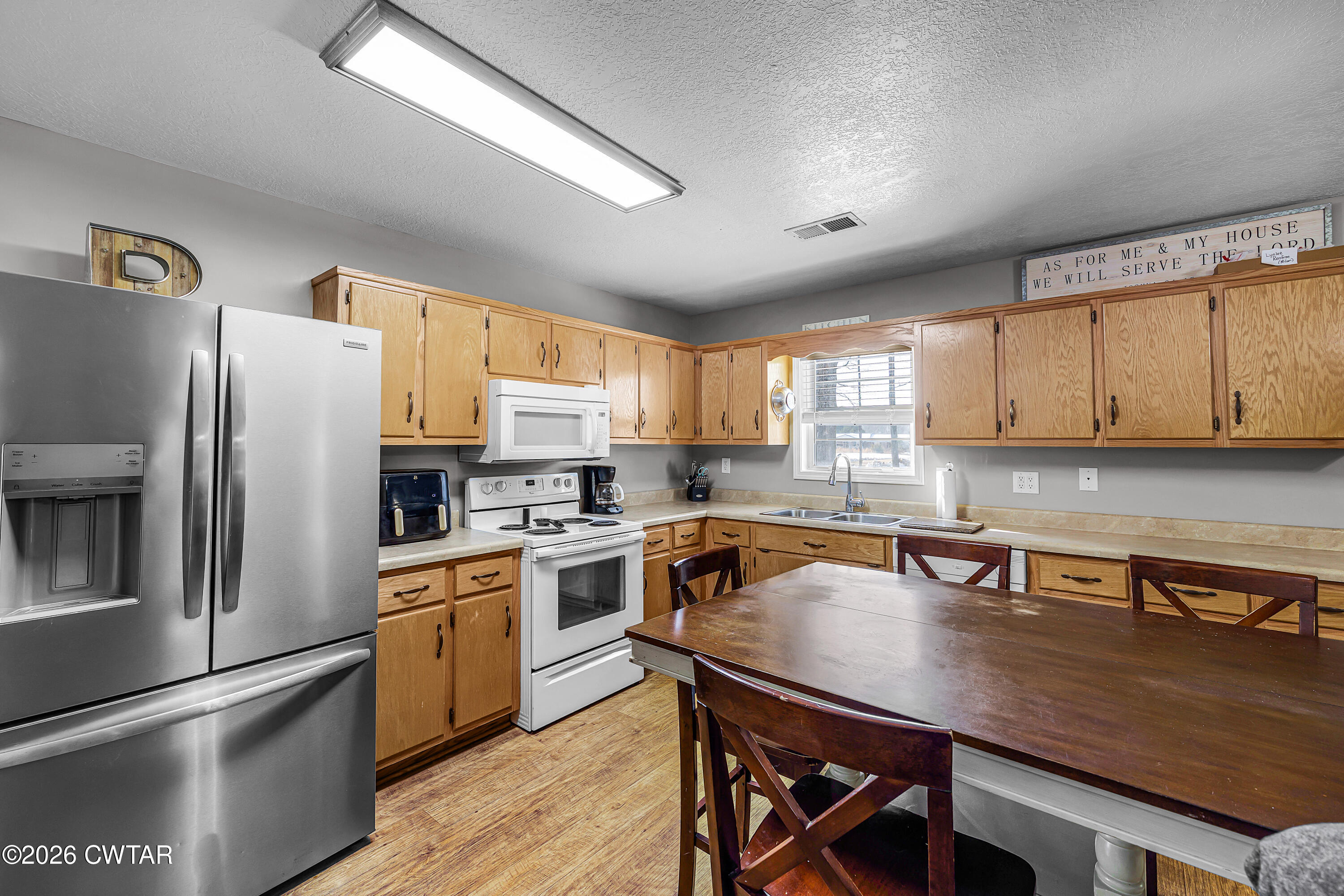 67 Robert Crocker Road Bradford, TN 38316 - Photo 6 of 20 a kitchen with a refrigerator a stove a sink dishwasher and white cabinets with wooden floor