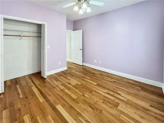 a view of an empty room with wooden floor fireplace and a window