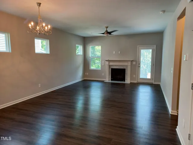 an empty room with wooden floor fireplace and windows
