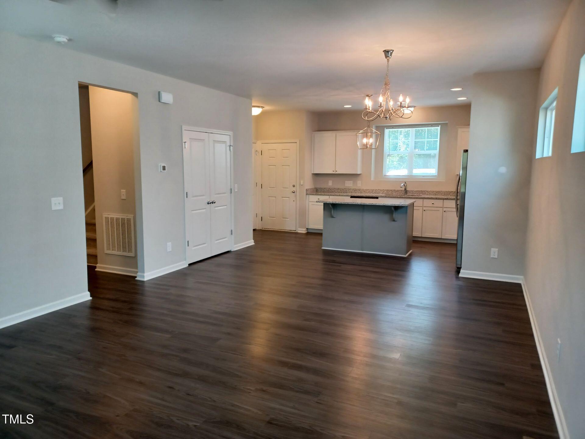 424 Cherry Street Fuquay-Varina, NC 27526 - Photo 5 of 28 an empty room with wooden floor and kitchen