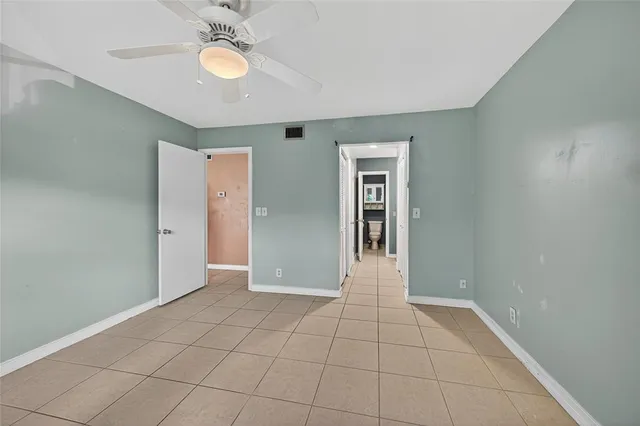 a view of an empty room with window and chandelier fan