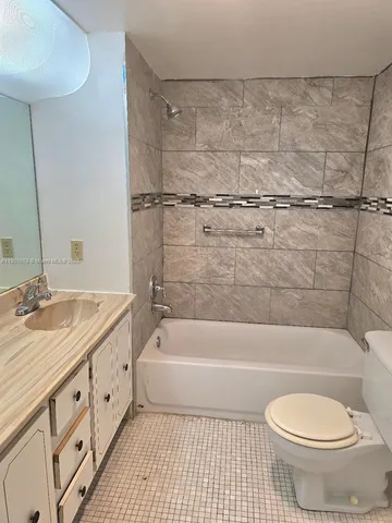 a bathroom with a granite countertop bathtub shower sink mirror and toilet