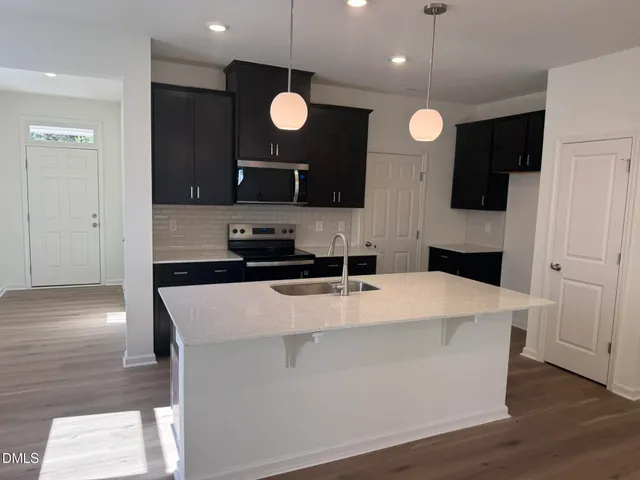 a large kitchen with stainless steel appliances a large counter top a refrigerator and a stove top oven